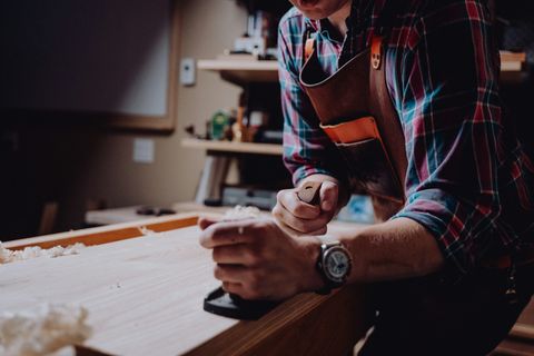 Tischler in Arbeitsschürze an der Werkbank