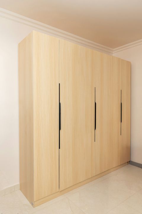 Raumhoher Einbauschrank aus hellem Holz mit schwarzen Griffleisten